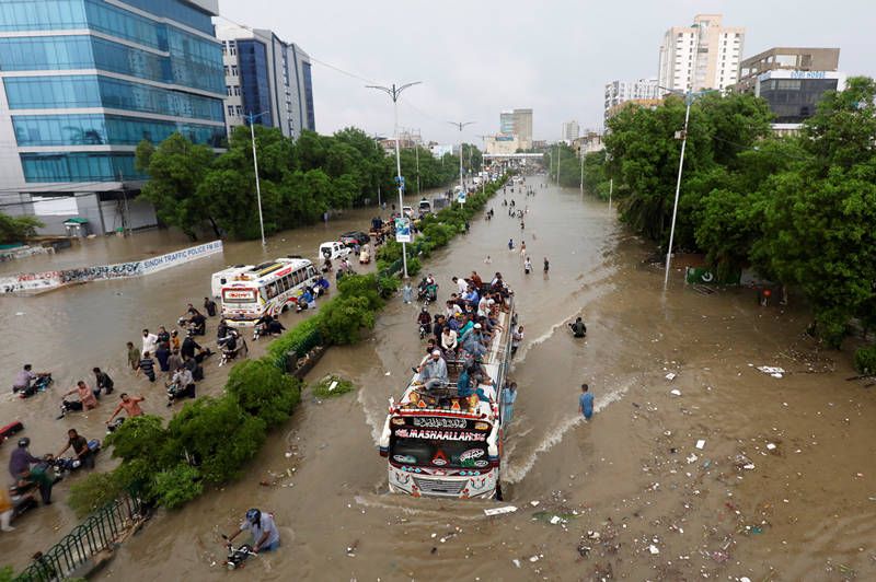 当地时间2020年8月27日,巴基斯坦卡拉奇,暴雨过后街道被淹没,民众在