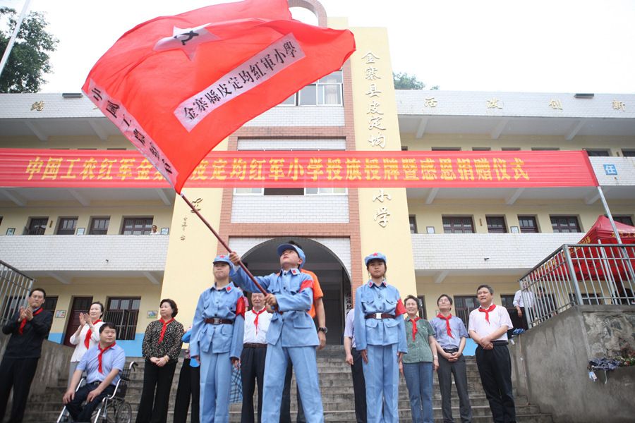 图为金寨县皮定均红军小学的学生挥舞红军小学校旗.