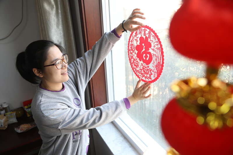 兖州工务段团委工作人员在贴窗花,营造过年氛围.