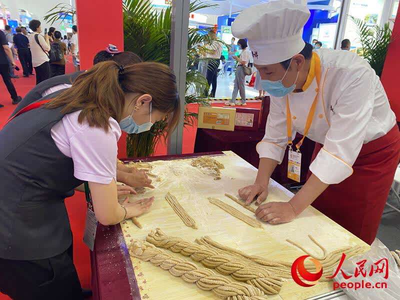 消博会天津馆内,参观观众正在制作天津十八街麻花。人民网记者 杜燕飞摄