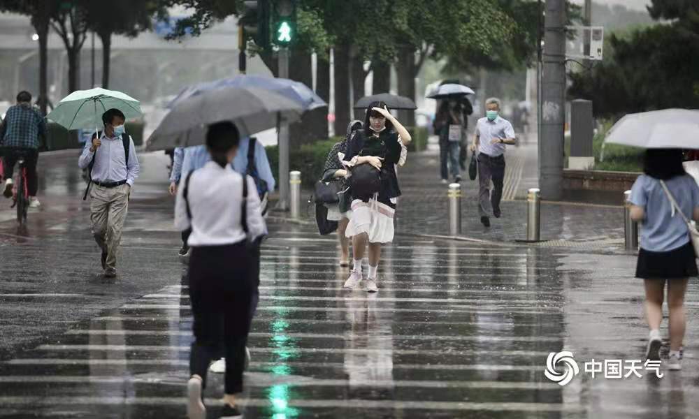 北京雷声滚滚迎来降雨 早高峰行人冒雨出行