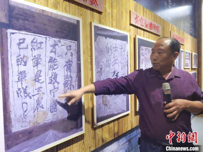 华朝良向记者展示精心守护的红军宣传标语图片。 周燕玲 摄