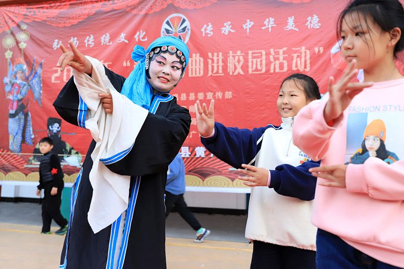 2021年10月19日,演员在河南省温县西关小学指导学生学习豫剧表演技巧.