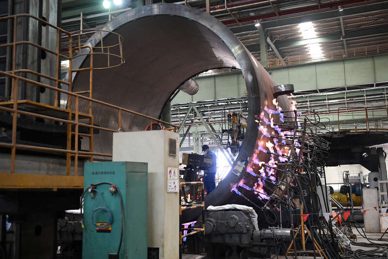 2022年4月23日，上海电气，工人在对机器部件进行热处理。