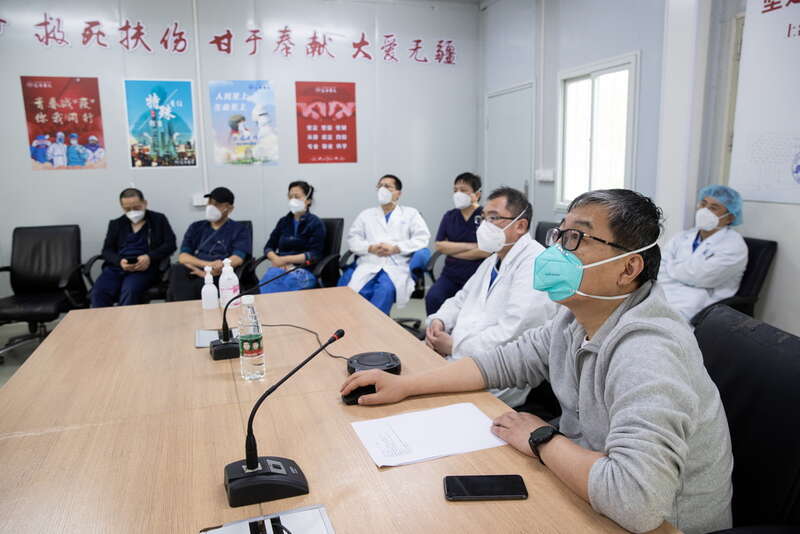 工作站内,身穿防护服,全副武装的医生护士正忙碌着:记录病人信息,接听