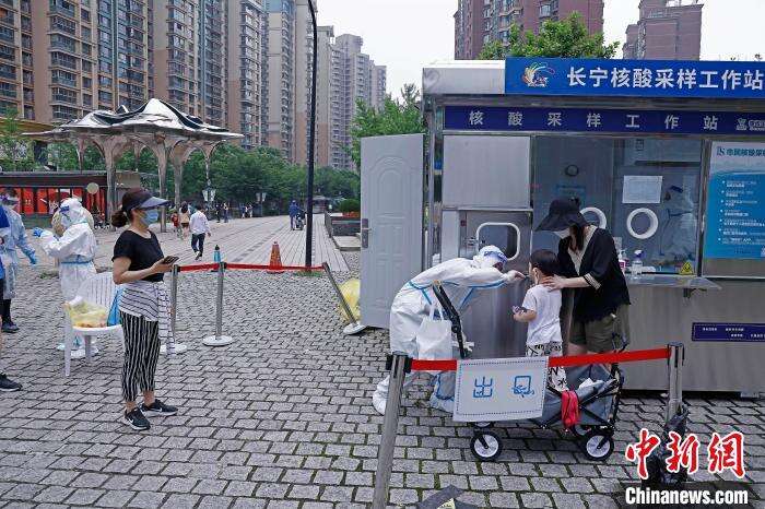 市民带着孩子在黄金城道步行街长宁核酸采样工作站进行核酸采样。 殷立勤 摄