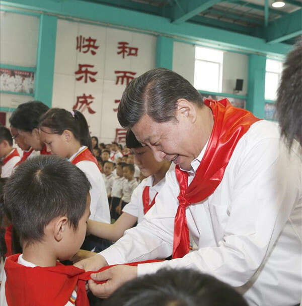 2014年5月30日，在北京市海淀区民族小学的少先队入队仪式上，习近平为新少先队员系上红领巾。