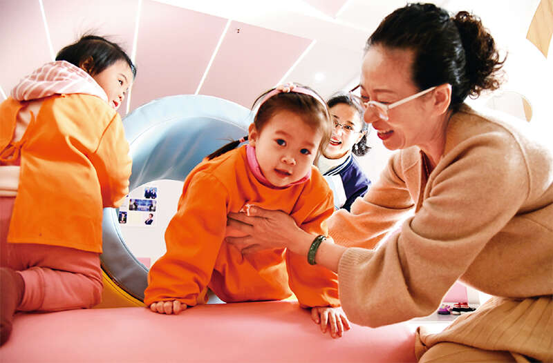 为解决0—3岁婴幼儿的照护问题，促进人口长期均衡发展，近年来，从中央到地方，各级政府相继出台政策鼓励和支持发展婴幼儿托育服务。图为2021年11月2日，在江苏省连云港市海州区新海街道小红花托育中心，小朋友在老师带领下快乐地做游戏。 求是图片 耿玉和/摄