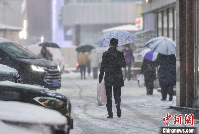降雪天气，市民撑伞外出。　刘新 摄