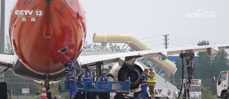 Airport worker adjusts high pole lights during summer heat.